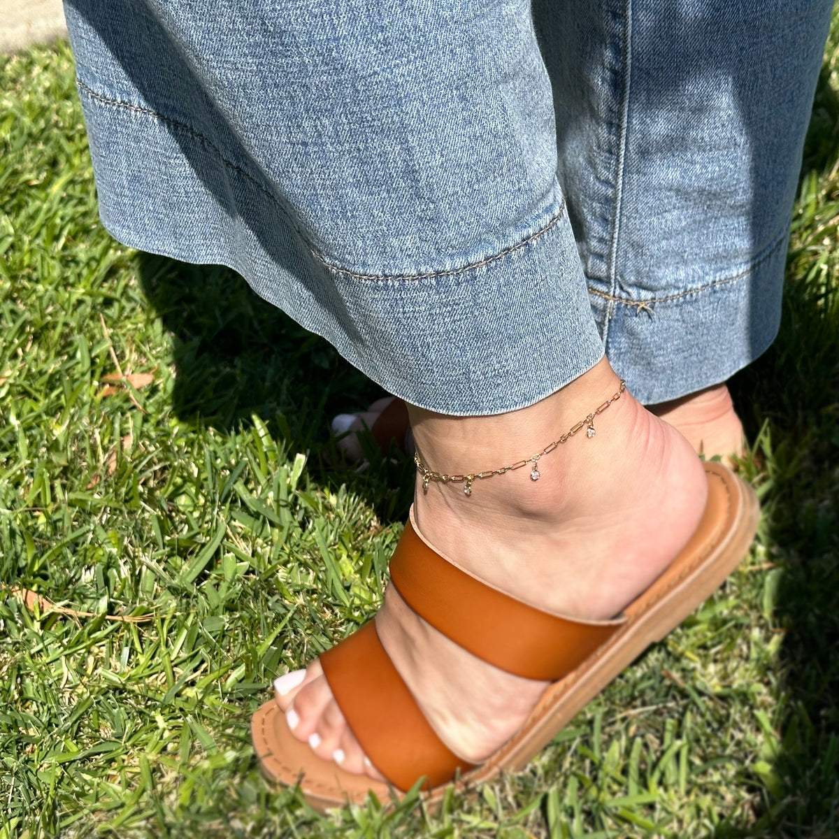 Model wearing an 18k gold filled paperclip chain anklet with bezel CZ drops, showcasing contemporary ankle jewelry.