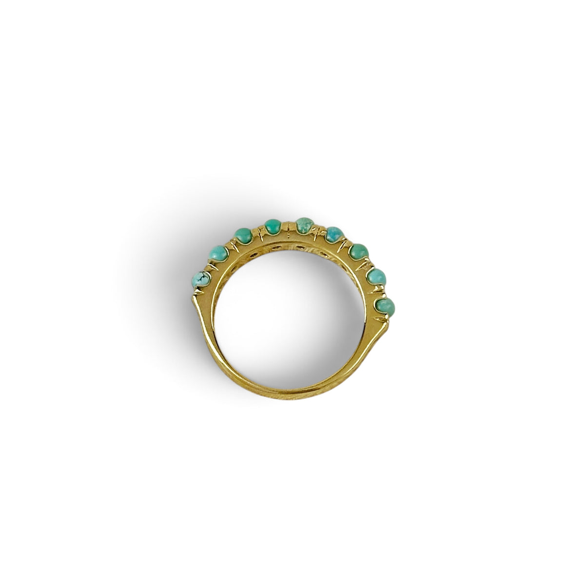 A gold ring featuring a row of small turquoise-colored gemstones set along the top, photographed on a clean white background.