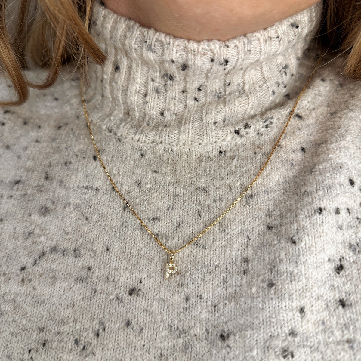 Letter P pavé CZ initial charm necklace in 18K gold-filled worn over a knit sweater