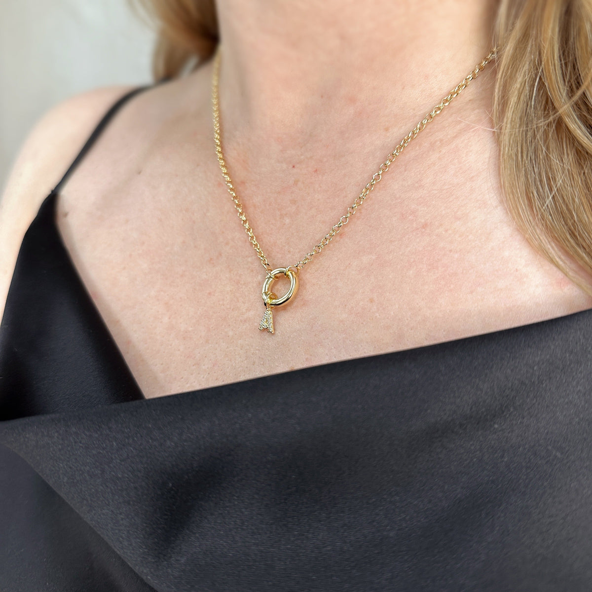 Woman wearing a pavé CZ initial charm necklace in 18K gold-filled