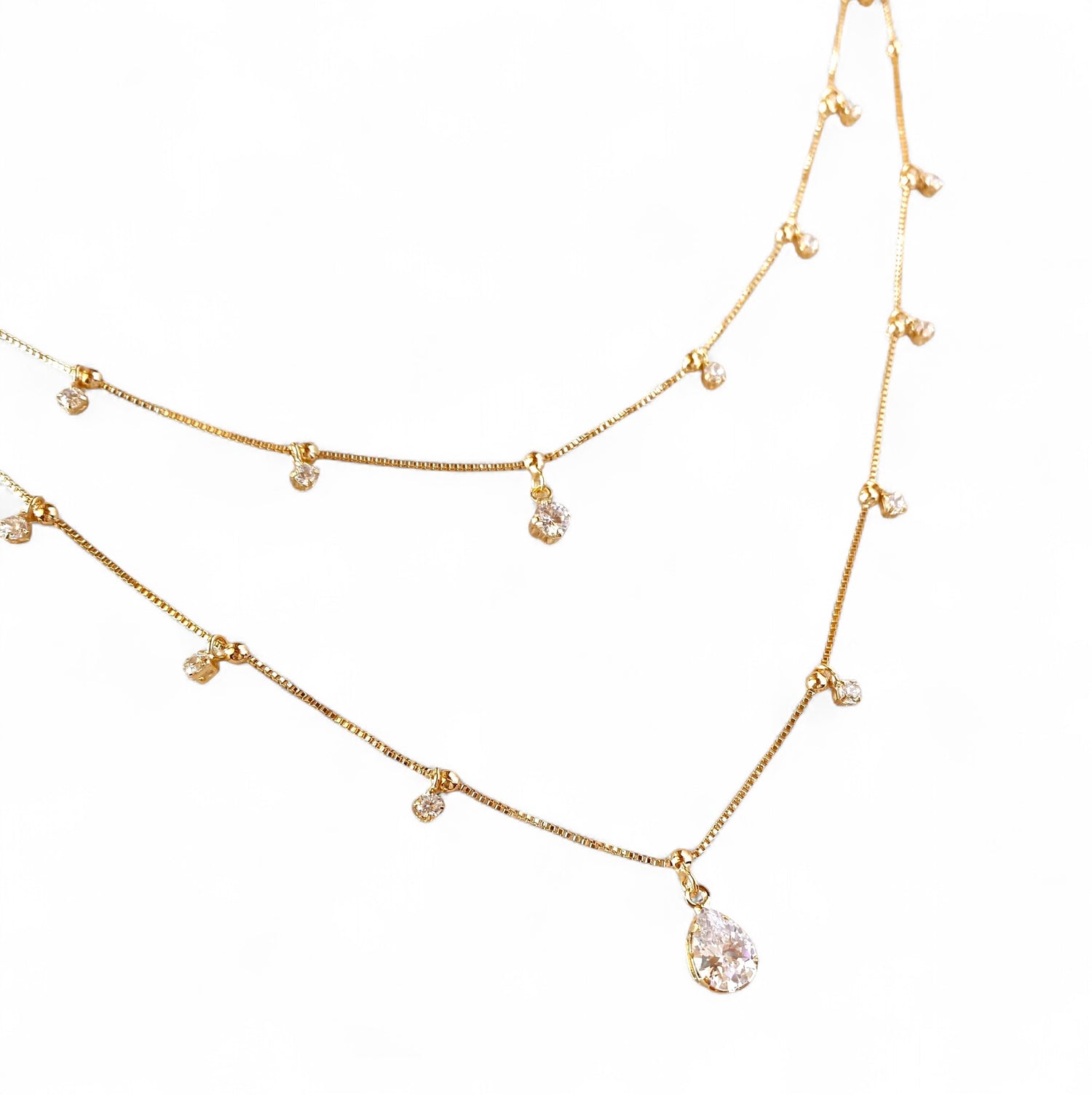 A gold-toned double-layer necklace featuring a teardrop-shaped clear crystal pendant