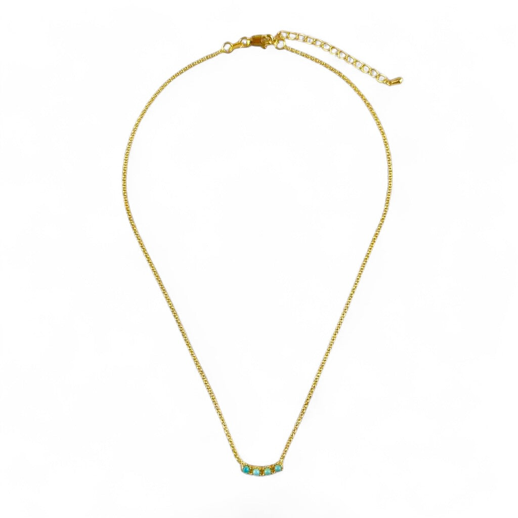 A gold chain necklace with a small curved bar pendant featuring turquoise and gold details, displayed on a clean white background.