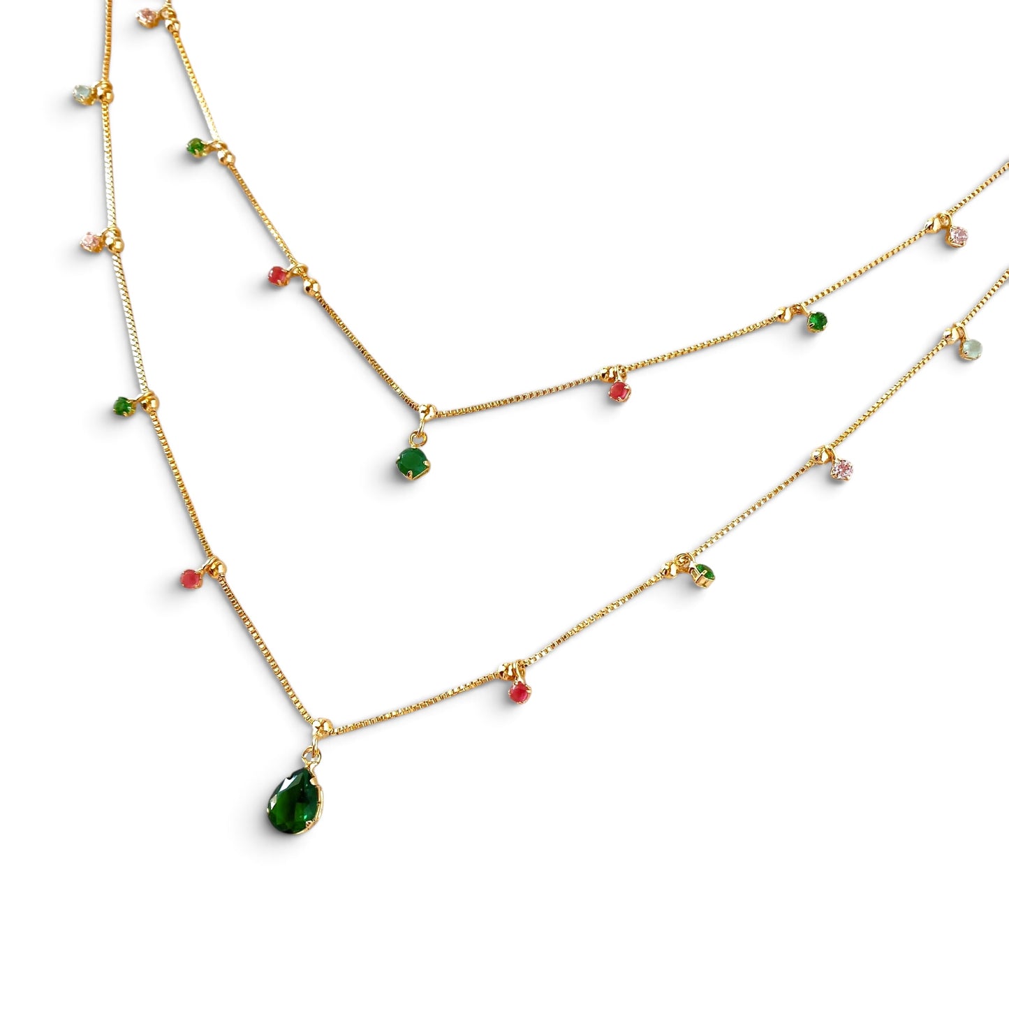 A gold layered necklace set featuring a teardrop-shaped green gemstone pendant, small green and pink stones, and clear accent stones on a white background.