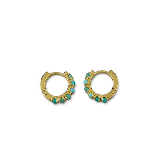 A pair of gold huggie hoop earrings decorated with small turquoise-colored stones, shown against a plain white background.