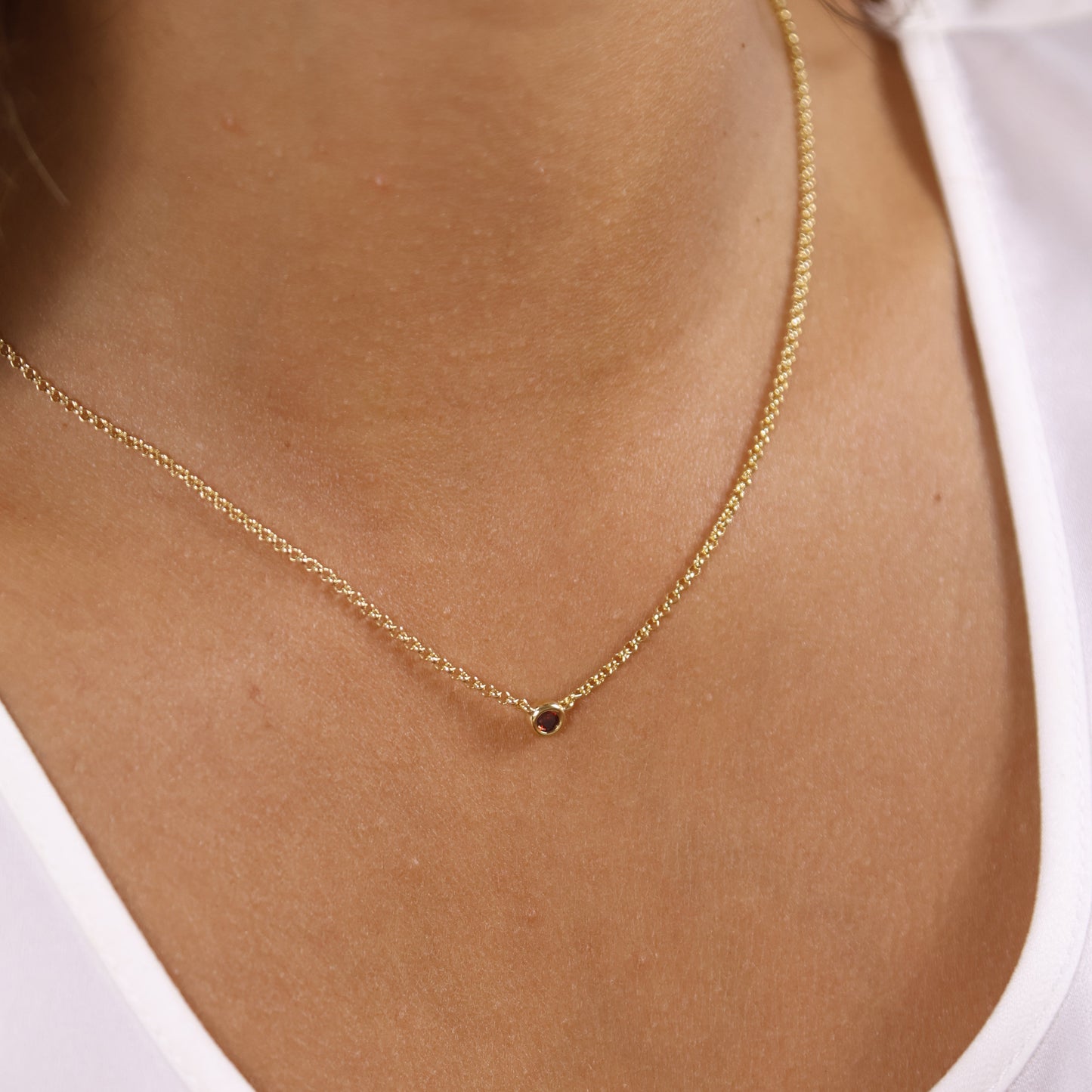 Gold necklace on a person's neck with a plain background