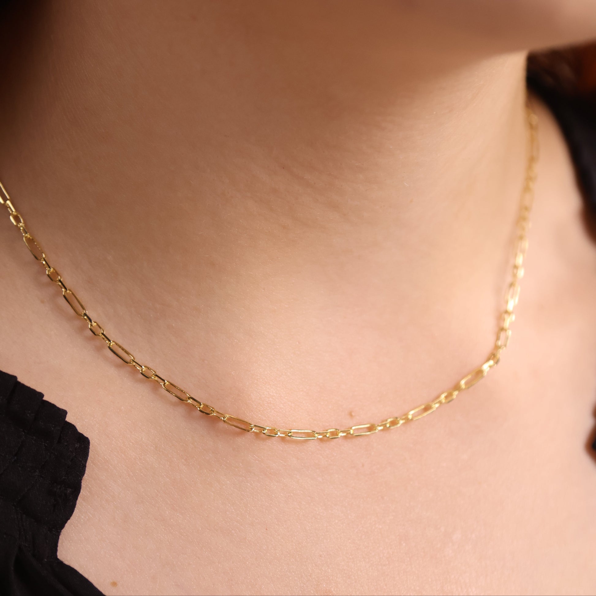 Gold necklace on a person's neck with a blurred background