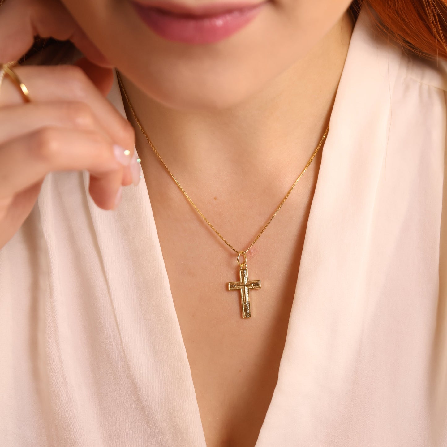 Close-up of a woman wearing a gold necklace with a cross pendant.