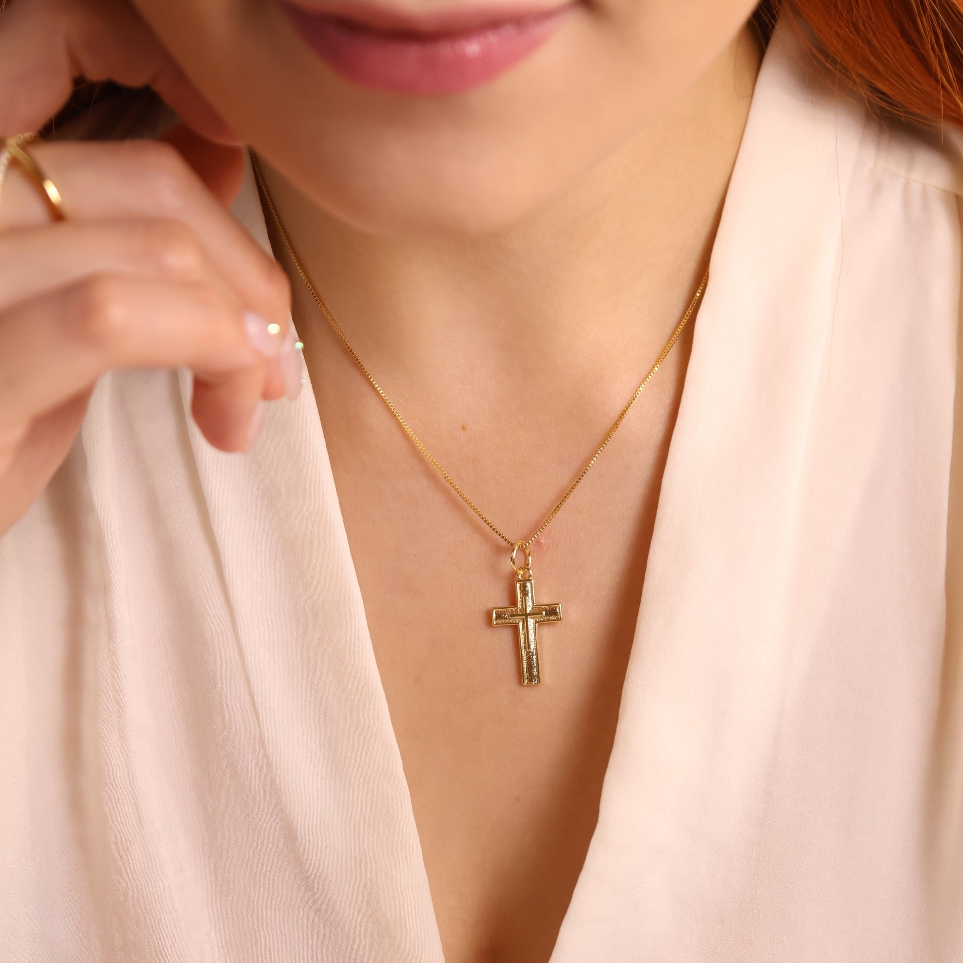 Close-up of a woman wearing a gold necklace with a cross pendant.