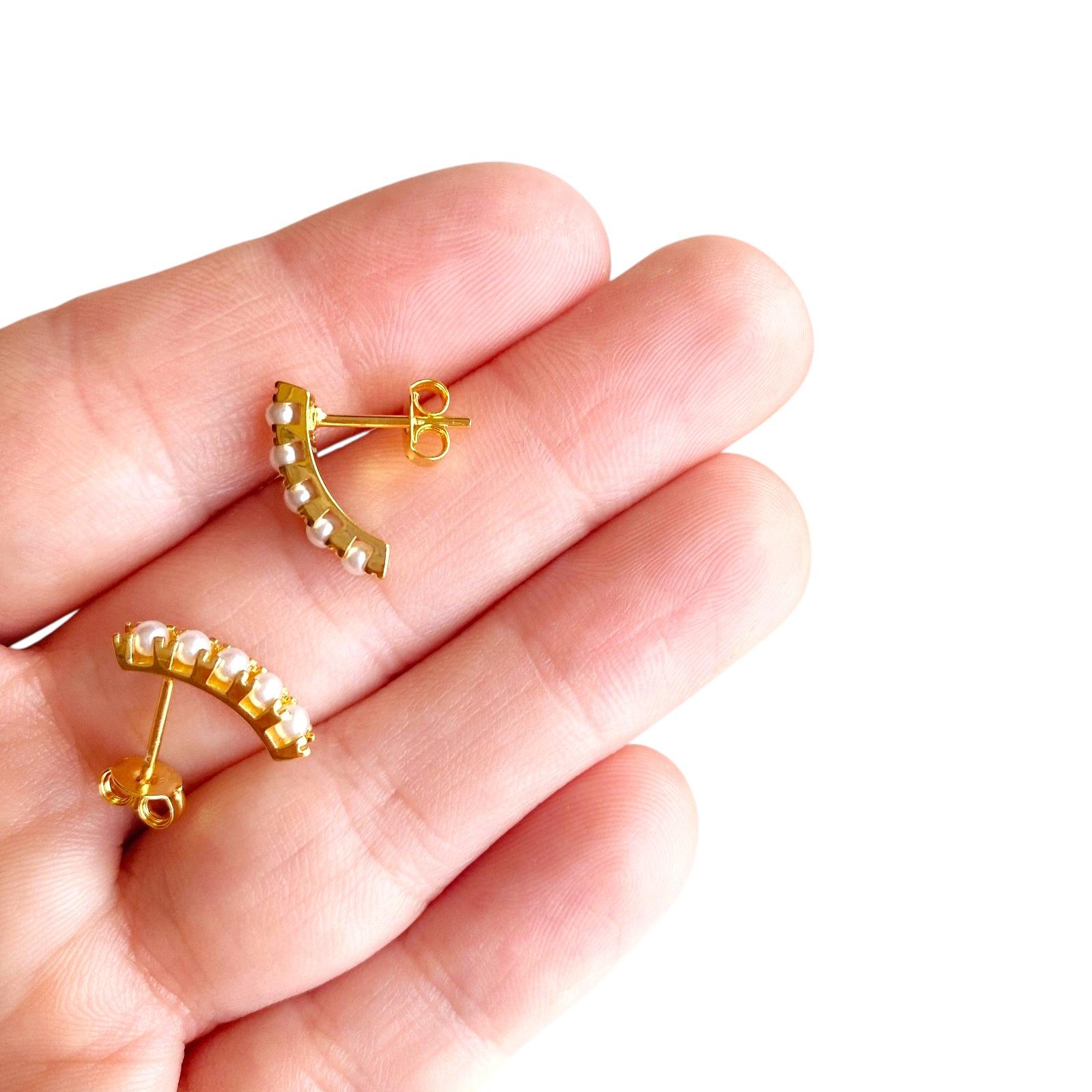 Skillud 18k Gold-filled pearl earrings  held between fingers on a white background