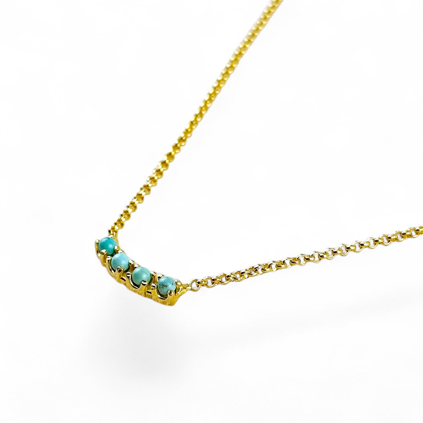 A gold chain necklace featuring a curved bar pendant with round turquoise-blue stones, photographed on a clean white background.