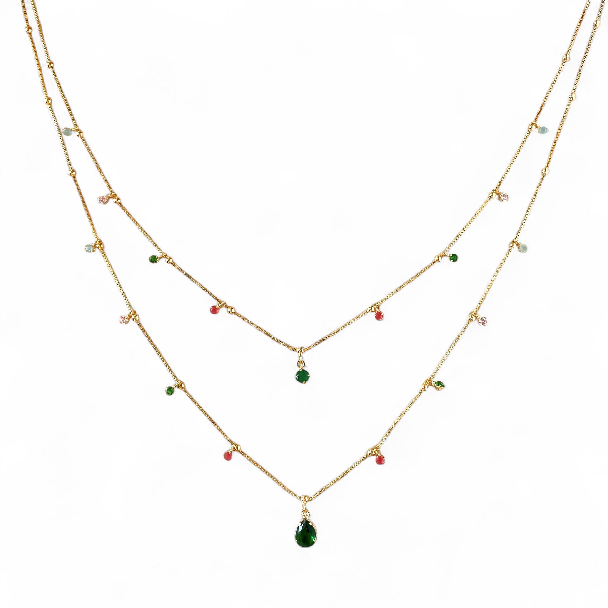 A double-layered gold necklace with small colorful gemstone beads and a teardrop-shaped green pendant, displayed on a solid white background.